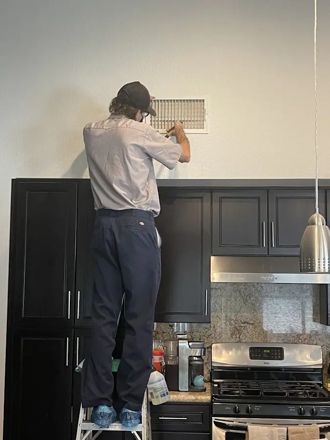 Technician inspecting an air vent during HVAC service in Menifee